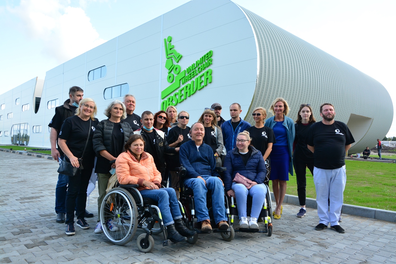 Роман Аранин (на коляске в центре) вместе с гостями фестиваля у здания завода по производству инвалидных колясок Observer 